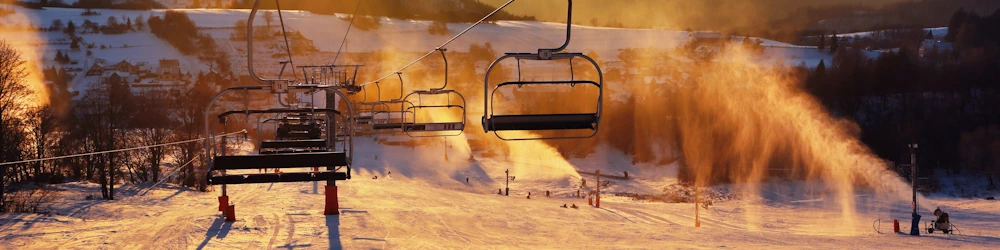 Snow cannons in action at sunrise on a slope in the Alps